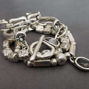 Set of 5 stacking silver plated bracelets on a grey background ( 2 cuffs, 1 toggle clasp bracelet, 2 beaded bracelets )