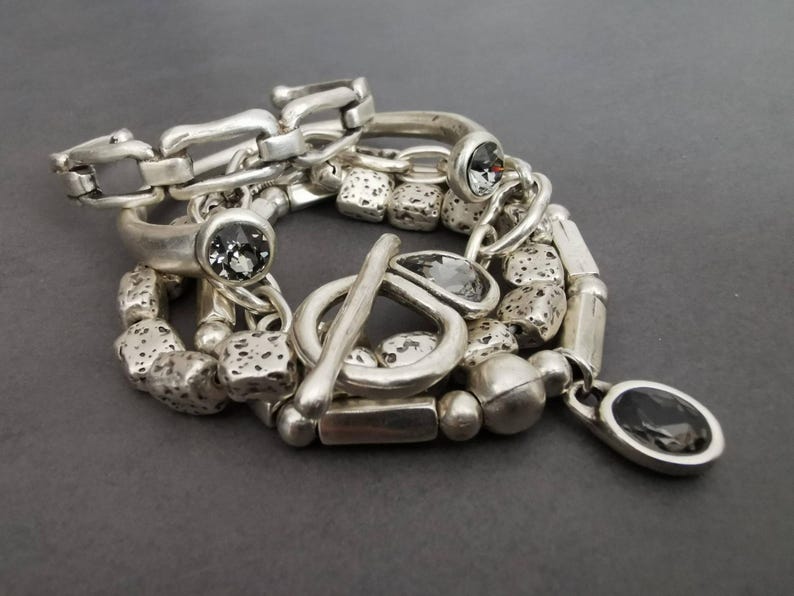 Set of 5 stacking silver plated bracelets on a grey background ( 2 cuffs, 1 toggle clasp bracelet, 2 beaded bracelets )