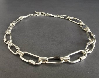 May include: A silver chain necklace with large, oval-shaped links. The links are connected with smaller, round links.