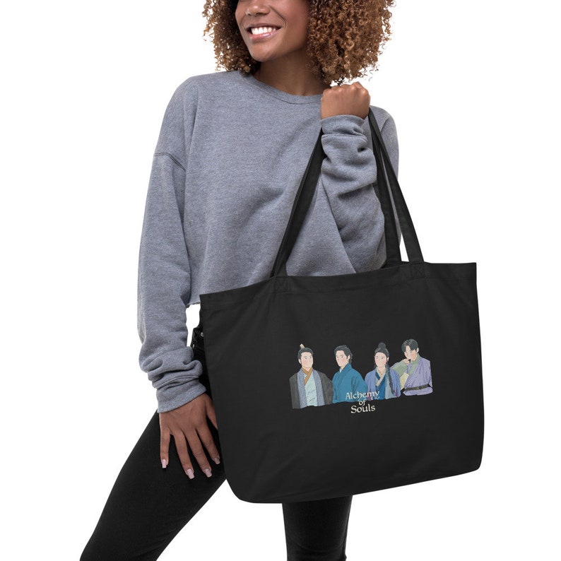 May include: Black tote bag with a white graphic of four people in traditional Korean clothing. The text "Alchemy of Souls" is below the image.