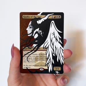 May include: A Magic: The Gathering trading card featuring an altered art illustration of Kaalia of the Vast. The card displays a profile of a figure with long black hair, white horns, and large white wings against a black and brown background.