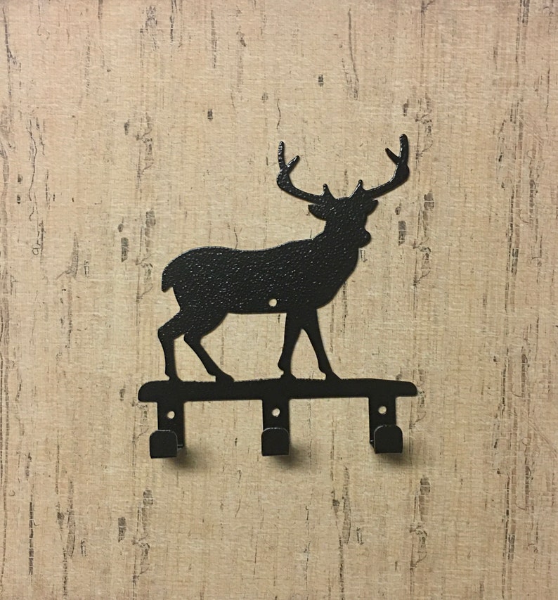 Op de afbeelding: Zwarte metalen sleutelhanger in de vorm van een hert silhouet met drie haken. Het hert staat op een metalen balk met de haken aan de onderkant bevestigd.
