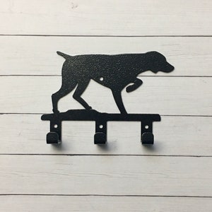 May include: Black metal key holder shaped like a German Shorthaired Pointer dog in a pointing position. The holder has three hooks.