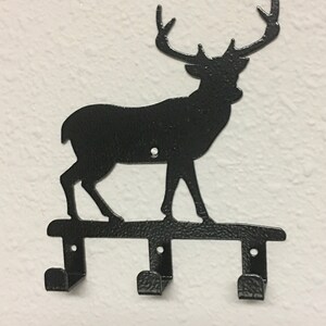 Op de afbeelding: Zwarte metalen hert silhouet wandhaak met drie haken.