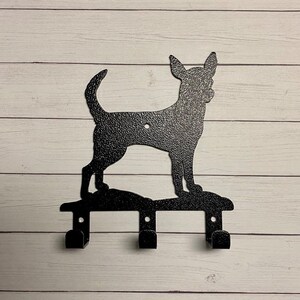 Puede incluir: Porta llaves de metal negro con forma de perro chihuahua con tres ganchos.