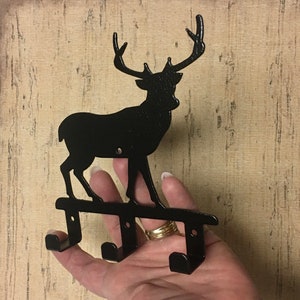 Op de afbeelding: Zwarte metalen hert silhouet wandhaak met drie haken.