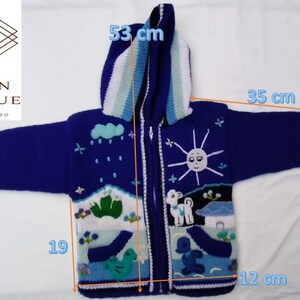 Puede incluir: Un suéter azul con capucha y cremallera con un diseño caprichoso. El suéter presenta un sol, nubes y figuras de animales. La capucha mide 53 cm, la longitud de la manga es de 35 cm y el ancho inferior es de 12 cm. El logotipo de la marca es visible.