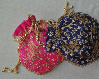 May include: Two embroidered drawstring bags, one pink and one blue, with gold thread and beads. The bags are decorated with floral patterns.