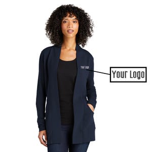 May include: A woman wearing a navy blue cardigan with a black top and dark blue jeans. The cardigan has long sleeves, pockets, and the text "Your Logo" on the front.