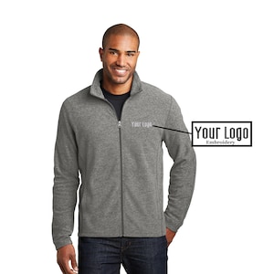 May include: A gray fleece zip-up jacket with a stand-up collar. The jacket has a small embroidered logo on the left chest that says "Your Logo".