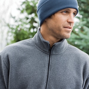 May include: A man wearing a gray fleece pullover with a zipper and a blue knit beanie.