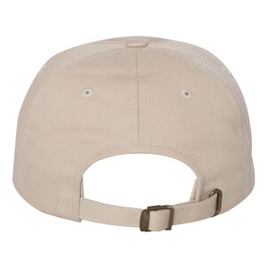 Puede incluir: Una gorra de b&eacute;isbol de color beige liso con una construcci&oacute;n de seis paneles y ojales cosidos en cada panel. La parte posterior de la gorra incluye una correa de tela ajustable con una hebilla deslizante de metal en tono bronce.