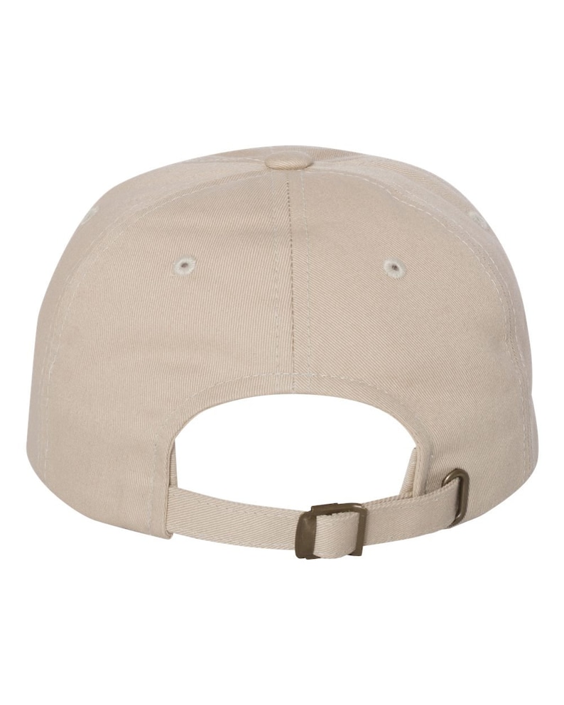 Puede incluir: Una gorra de b&eacute;isbol de color beige liso con una construcci&oacute;n de seis paneles y ojales cosidos en cada panel. La parte posterior de la gorra incluye una correa de tela ajustable con una hebilla deslizante de metal en tono bronce.