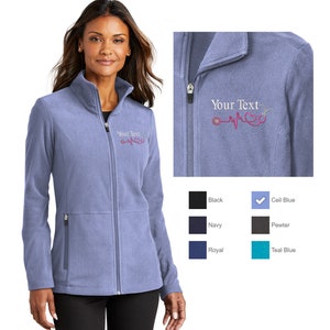 May include: A light blue fleece jacket with a zipper closure and two front pockets. The jacket has a  "Your Text" embroidery with a stethoscope and a heart beat graphic. The jacket is available in a variety of colors, including black, navy, royal, pewter, teal blue, and cell blue.