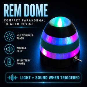 Puede incluir: Un dispositivo de activación paranormal en forma de cúpula negra etiquetado como REM DOME. Presenta bandas de luz horizontales en verde, azul y morado, un interruptor de palanca de metal en el lateral y texto que indica funciones como flash multicolor, pitido audible y alimentación por batería de 9V.