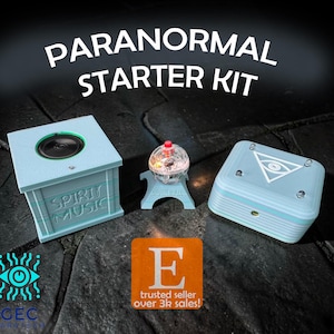Puede incluir: Un kit de inicio paranormal con tres dispositivos azul claro. El kit incluye un altavoz con el texto "SPIRIT MUSIC", un orbe brillante y una caja con un símbolo de ojo. También está presente el texto "PARANORMAL STARTER KIT".