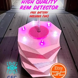 May include: A pink REM detector with a geometric design, featuring a central rod and illuminated lights. The text "HIGH QUALITY REM DETECTOR" and "FREE BATTERY INCLUDED (UK)" are visible. The Etsy logo is also present.