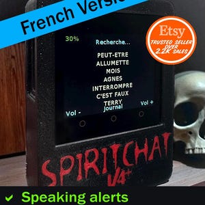 May include: A black electronic device with a screen displaying text in French, including "Recherche..." and "Terry Journal." The device has red lettering that says "SPIRITCHAT V4+" and green checkmarks below. An Etsy trusted seller badge is visible.
