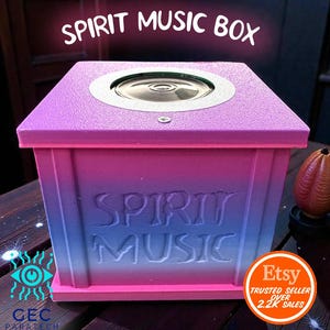 Puede incluir: Caja de música rectangular con degradado de color rosa, morado y azul. La parte superior presenta un altavoz plateado. Las palabras "SPIRIT MUSIC BOX" están impresas en la parte superior y frontal. El logotipo de Etsy es visible.