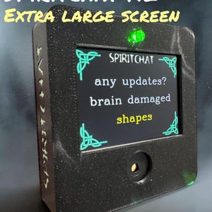 May include: A black Spiritchat XL extra large screen device with a green light on top. The screen displays the text "Spiritchat", "any updates?", "brain damaged", and "shapes".