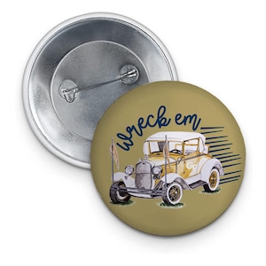 May include: A gold button with a vintage car illustration and the text "wreck em" in navy blue. The car is yellow with a white top and has a blue "GT" on the side.