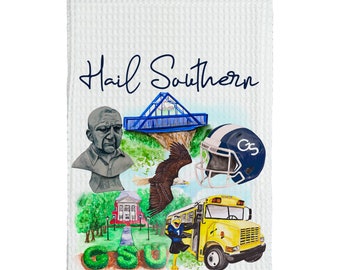 May include: A white waffle weave kitchen towel with a blue and green watercolor illustration of a college campus. The illustration includes a bridge, a building, a bus, an eagle, a football helmet, and a bust of a man. The text "Hail Southern" is written in blue cursive at the top of the towel.