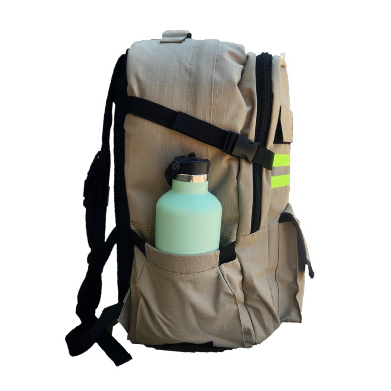 Puede incluir: Una mochila beige con correas negras y una franja reflectante verde. Una botella de agua azul claro est&aacute; en el bolsillo lateral.