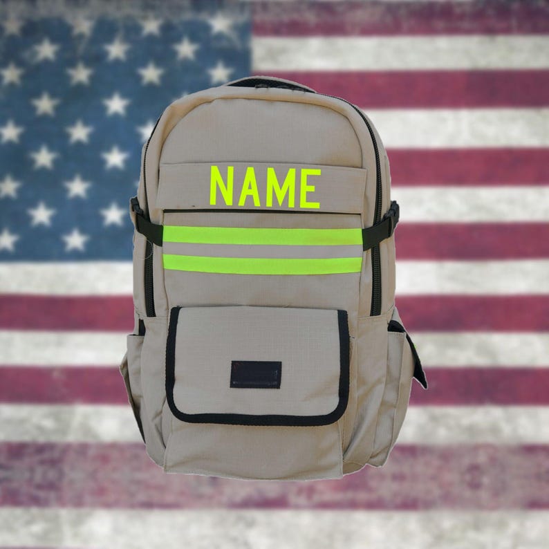 Puede incluir: Una mochila beige con dos rayas reflectantes de color verde lima y la palabra "NAME" en letras amarillas en la parte delantera.