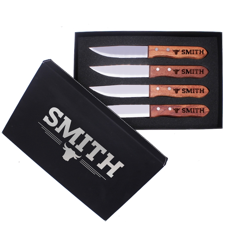 May include: A set of four steak knives with wooden handles in a black box. The knives have a silver blade and the handles are engraved with the name "SMITH" and a bull's head.