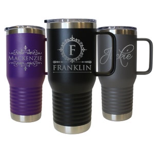 Pode incluir: Tr&ecirc;s canecas de viagem personalizadas em a&ccedil;o inoxid&aacute;vel com al&ccedil;as. Uma &eacute; roxa com "Mackenzie" em escrita, uma &eacute; preta com "Franklin" e uma inicial, e uma &eacute; cinza com "Jackie" em escrita. Cada caneca tem uma borda e uma tampa prateadas.