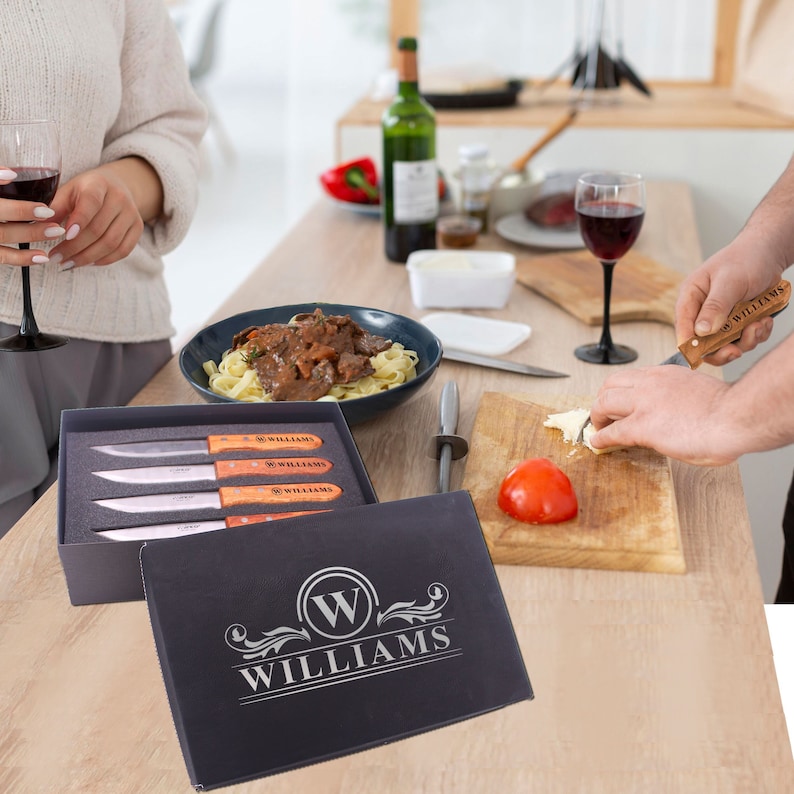 May include: A set of four steak knives with wooden handles in a black box. The box has the name "WILLIAMS" engraved on it in silver lettering. The knives have the name "WILLIAMS" engraved on the handles.