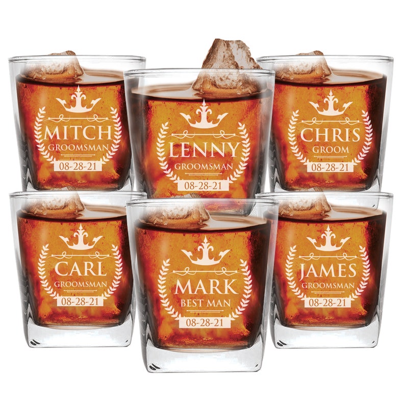 Peut inclure: Six verres &agrave; whisky en verre transparent remplis d'un liquide brun. Chaque verre est d&eacute;cor&eacute; d'un motif blanc avec une couronne, un nom et un titre, tels que "Groom", "Best Man" et "Groomsman". La date "08-28-21" est imprim&eacute;e sur chaque verre.