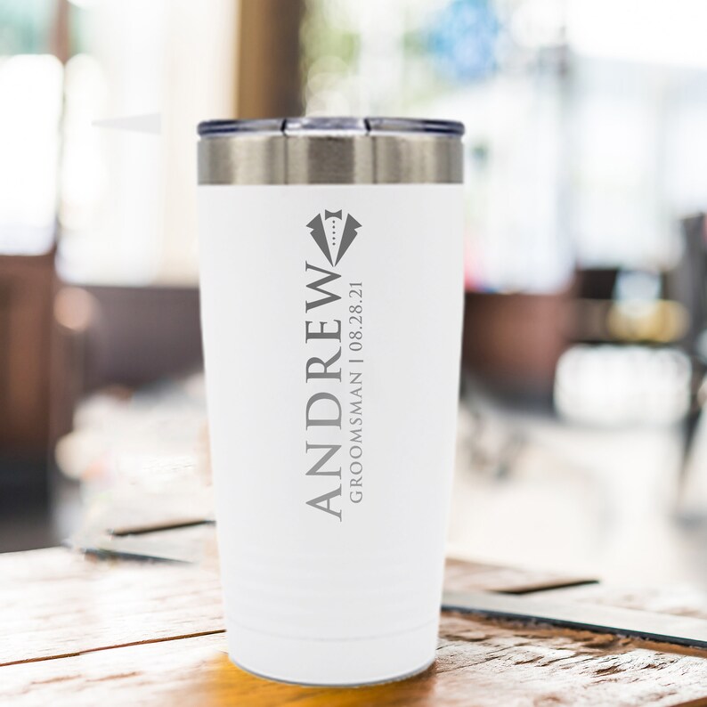 May include: White stainless steel tumbler with a gray inscription that reads "ANDREW GROOMSMAN | 08.28.21" and a tuxedo graphic.