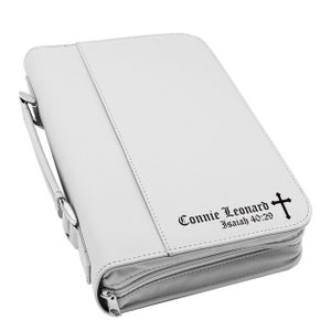 May include: A white Bible cover with a handle and zipper closure. The cover has the name "Connie Leonard" and the text "Isaiah 40:29" with a cross symbol printed on the front.
