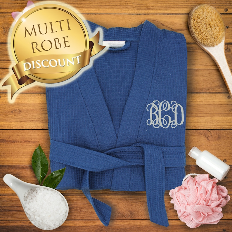 May include: A blue waffle weave robe with a white monogram "B.C.D." embroidered on the right side. The robe is tied with a matching blue sash.