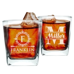 May include: Two clear glass whiskey glasses with a personalized design. The glass on the left has the letter "F" in a decorative frame and the word "FRANKLIN" below. The glass on the right has the letter "M" in a decorative frame and the word "Miller" below.