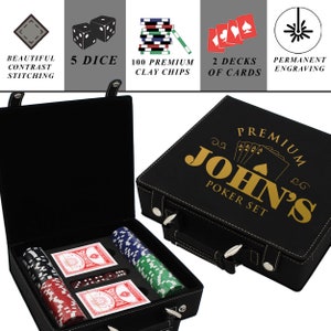 Puede incluir: Juego de p&oacute;quer de cuero negro con texto dorado "PREMIUM JOHN'S POKER SET". El juego incluye 100 fichas de arcilla, dos barajas de cartas y cinco dados. El estuche tiene un asa y cierres plateados.