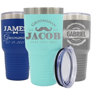 May include: Three stainless steel tumblers with lids. The tumblers are blue, turquoise, and gray. The blue tumbler has the name "JAMES" and the date "07-31-2021" engraved on it. The turquoise tumbler has the name "JACOB" and the date "JULY 31ST 2021" engraved on it. The gray tumbler has the name "GABRIEL" and the date "JULY 31ST 2021" engraved on it.