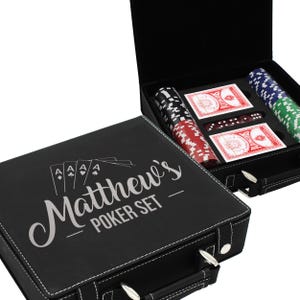Puede incluir: Juego de p&oacute;quer negro con costuras blancas, con el texto "Matthew's Poker Set". El juego incluye fichas de p&oacute;quer en rojo, negro, verde y azul, dos barajas de cartas y dados. El estuche tiene un asa y cierres met&aacute;licos.