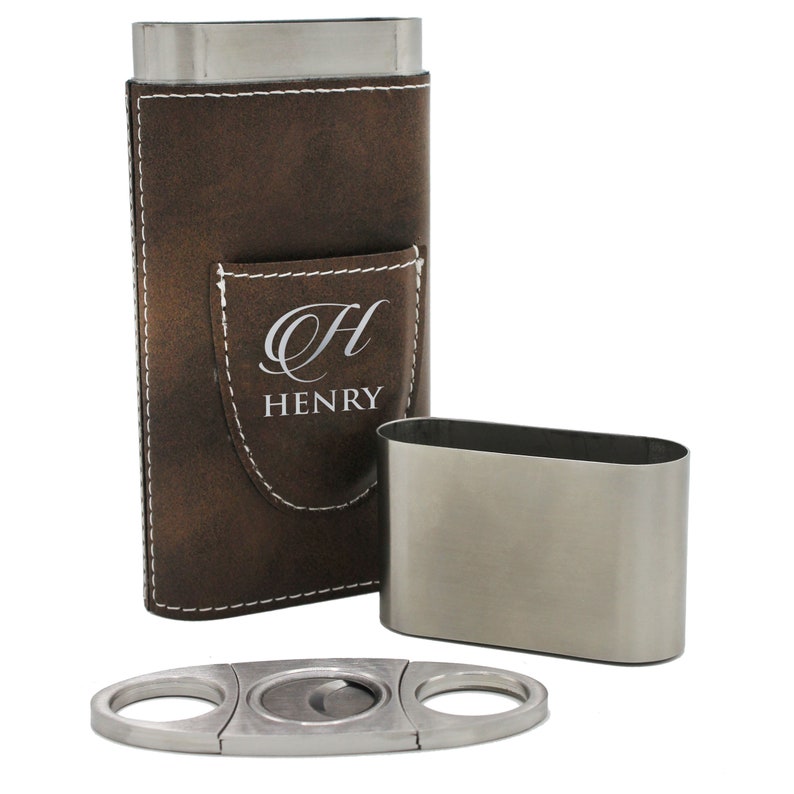 May include: A brown leather cigar case with white stitching and a pocket featuring the engraved letter H and the name HENRY. The set includes a matching stainless steel cigar case insert and a silver-toned metal cigar cutter with two finger holes.