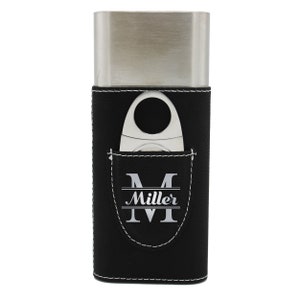 May include: A rectangular stainless steel cigar case with a black leather sleeve featuring white contrast stitching. A silver cigar cutter is tucked into a front pocket that displays the letter M and the name Miller in white lettering.