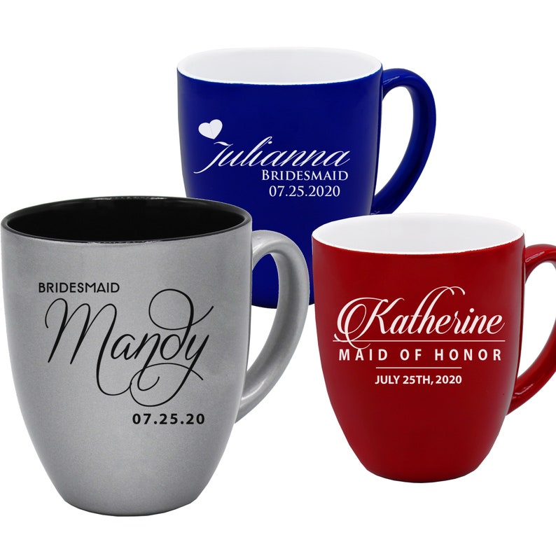 May include: Three ceramic mugs in blue, silver, and red. Each mug has a white interior and a curved handle. The blue mug has the name "Julianna" and "Bridesmaid" with a date. The silver mug has the name "Mandy" and "Bridesmaid" with a date. The red mug has the name "Katherine" and "Maid of Honor" with a date.