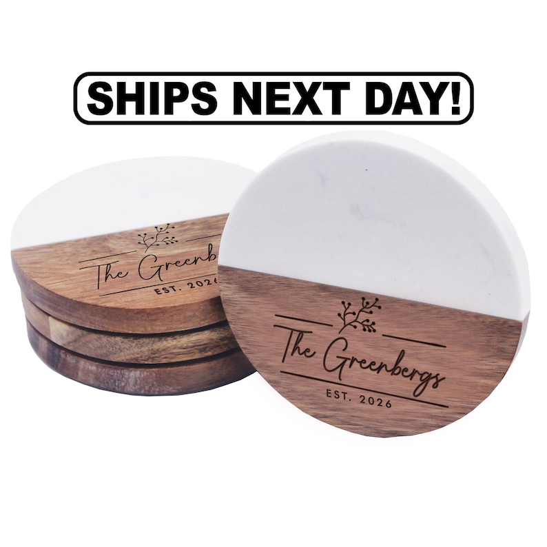 Puede incluir: Una pila de posavasos redondos con un dise&ntilde;o dividido de m&aacute;rmol blanco y madera marr&oacute;n. La secci&oacute;n de madera est&aacute; grabada con un gr&aacute;fico floral, el texto The Greenbergs y el texto EST. 2026. Sobre los posavasos aparece el texto SHIPS NEXT DAY!