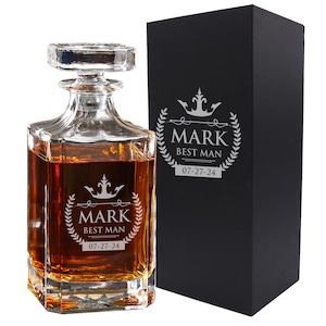 Peut inclure: Une carafe en verre transparent remplie d'un liquide ambr&eacute;, avec un bouchon carr&eacute; et une gravure repr&eacute;sentant une couronne, une couronne de laurier, le nom MARK, le texte BEST MAN et la date 07-27-24, &agrave; c&ocirc;t&eacute; d'une bo&icirc;te cadeau noire.