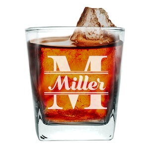 Peut inclure: Un verre carr&eacute; en verre transparent avec une grande lettre "M" et le mot "Miller" grav&eacute; sur le devant. Le verre est rempli d'un liquide fonc&eacute; et d'un gros gla&ccedil;on.