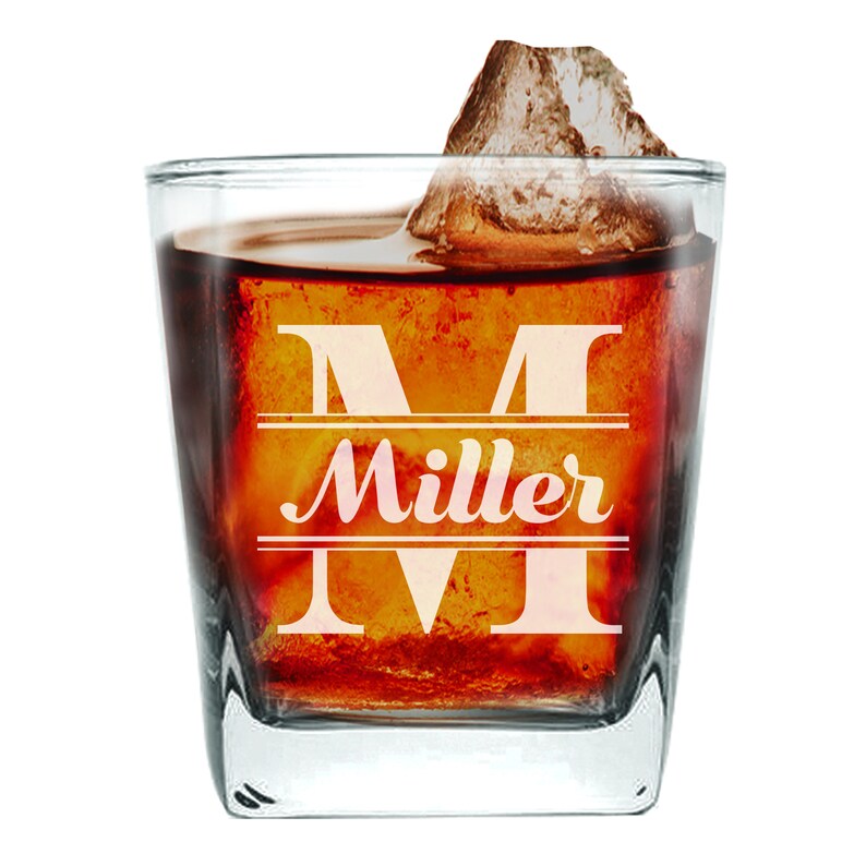 Peut inclure: Un verre carr&eacute; en verre transparent avec une grande lettre "M" et le mot "Miller" grav&eacute; sur le devant. Le verre est rempli d'un liquide fonc&eacute; et d'un gros gla&ccedil;on.