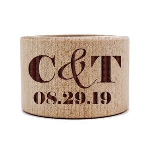 May include: A wooden ring holder engraved with the initials "C & T" and the date "08.29.19".