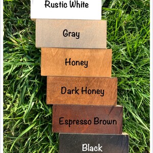 May include: Six wood samples stained in different colors: Rustic White, Gray, Honey, Dark Honey, Espresso Brown, and Black.