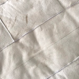 Pode incluir: Um cobertor branco de pel&uacute;cia acolchoado com uma textura macia e felpuda. O cobertor &eacute; feito de v&aacute;rios pain&eacute;is costurados juntos, criando um efeito de patchwork.