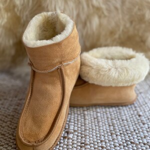Puede incluir: Un par de zapatillas de ante marr&oacute;n con forro de piel de oveja blanca. Las zapatillas tienen un pu&ntilde;o abatible y una punta puntiaguda.